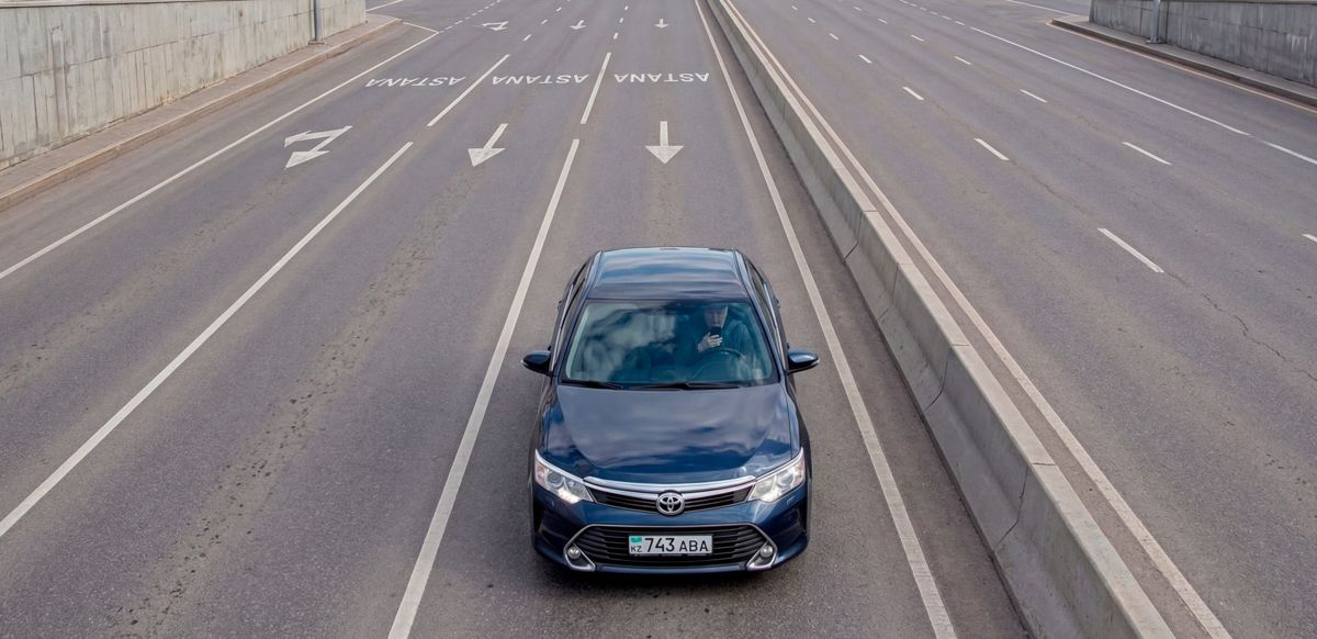 Мужчина за рулем в машине с телефоном в руках