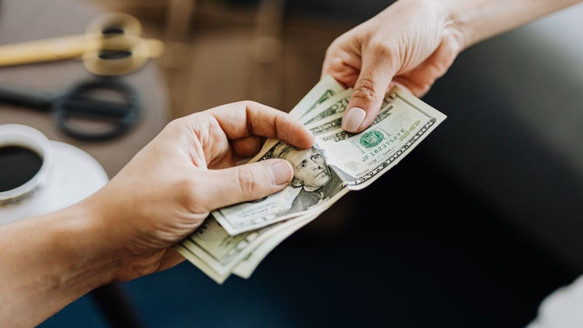 Мужчина передает женщине доллары