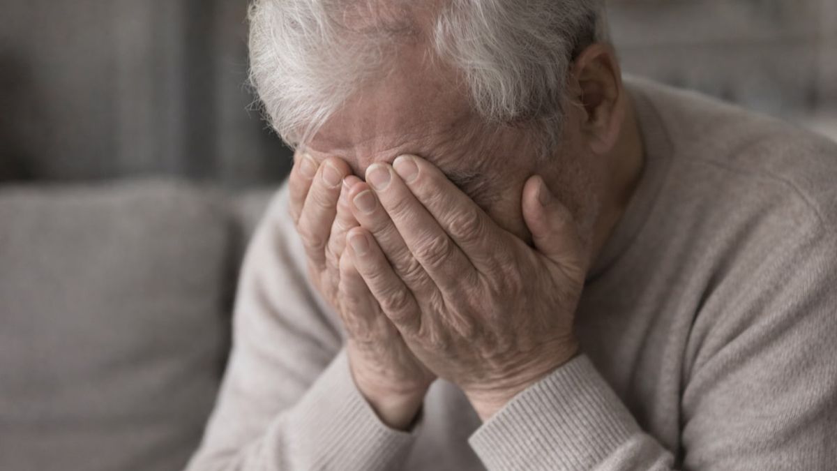 Пожилой мужчина закрывает лицо руками