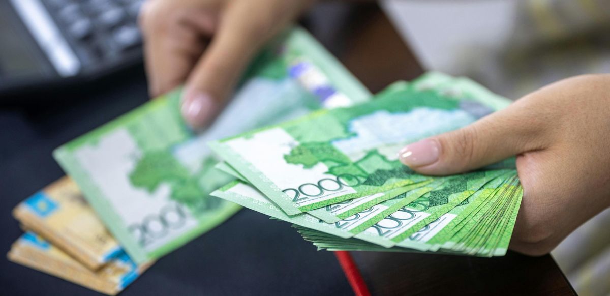 Женщина считает купюры казахстанских тенге 