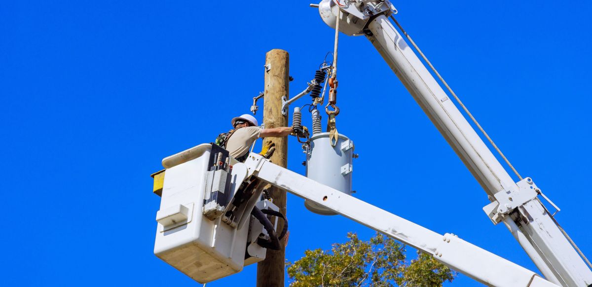 Коммунальный работник ремонтирует электрический столб
