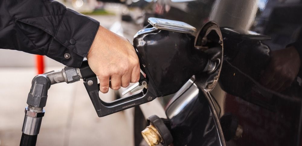 Человек, заправляющий черный автомобиль на заправке