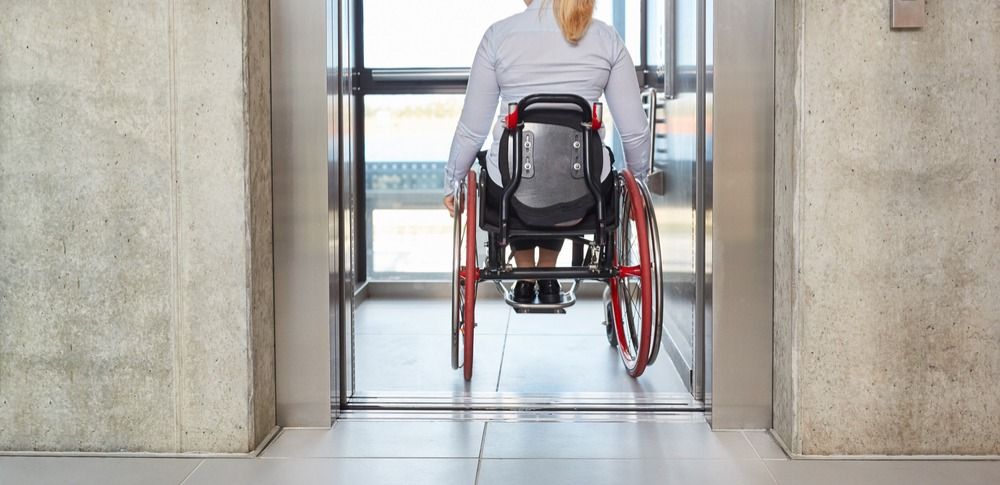 Женщина на инвалидной коляске заезжает в лифт