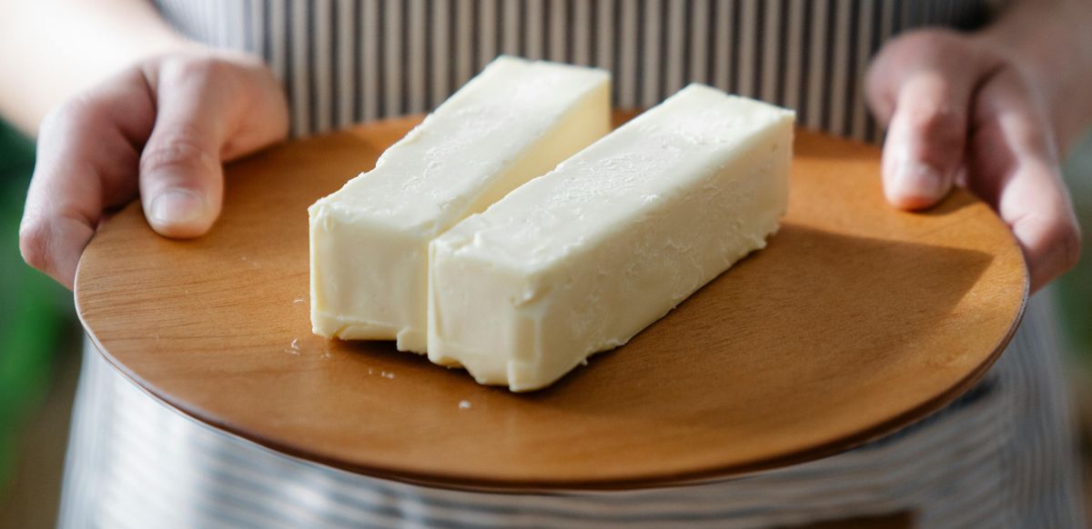 Женщина держит в руках тарелку со сливочным маслом